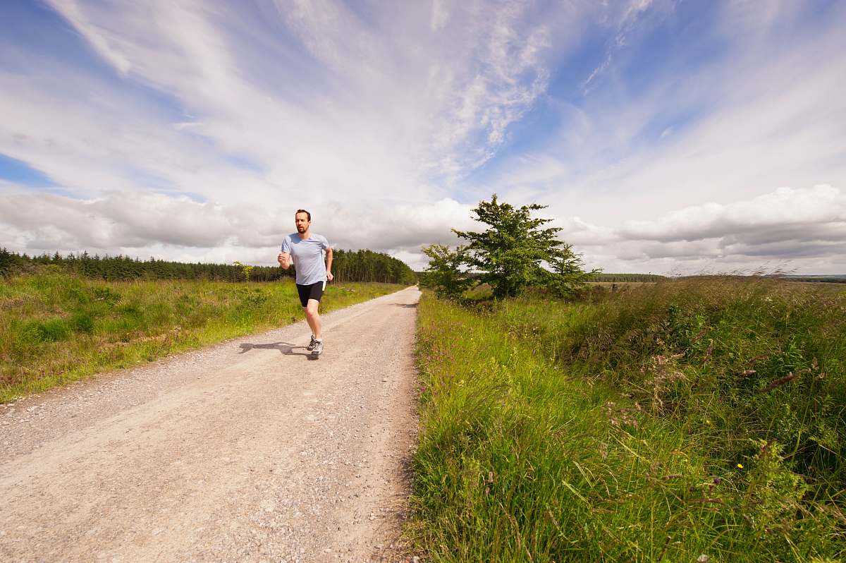 dirt road man running on dirt road under cloudy skies gravel